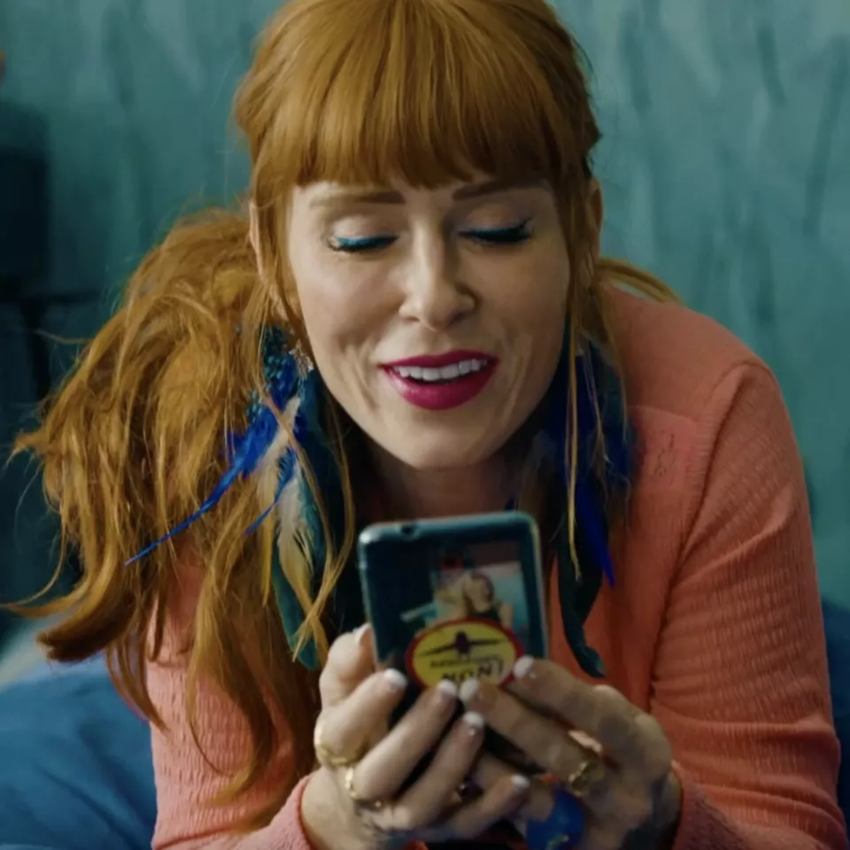 A smiling woman talking on the phone while lying in bed